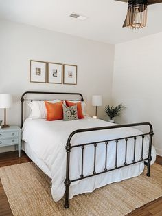 a bedroom with white bedding and orange pillows