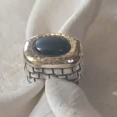 Fabulous And Bold Dian Malouf Ring In Sterling Silver And 14k. An Oval Black Gemstone Is Bezel Set East To West In A 14k Yellow Gold Hammered Setting. I Am Unsure What Stone This Is. It Is Not Onyx But Could Be An Obsidian. This Stands Up Half An Inch High On A Thick Sterling Band That Looks Like A Shingle Pattern Along The Sides. This Piece Is A Size 6. This Is Stamped Inside Dlm 14k And 925. This Is In Very Good Pre-Owned Condition With Some Scratching On The Band. Dian Malouf Rings, Elegant Wide Band Gemstone Jewelry, Elegant Black Rings With Gemstone Accents, Formal Silver Sapphire Ring With Gemstone Accents, Elegant Silver Sapphire Ring With Stone Setting, Elegant Black Jewelry With Large Stone, Elegant White Gold Jewelry With Large Stone, Elegant Sterling Silver Sapphire Ring With Large Stone, Elegant Large Stone Sapphire Ring In Sterling Silver