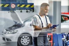 a man working in a car repair shop looking at something on his clipboard stock photo