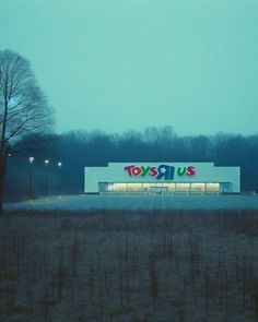 an empty parking lot in front of a toy store with the lights on at night