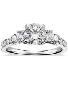 a three stone engagement ring with diamonds on the band and an oval cut diamond in the center