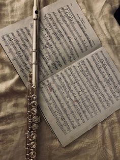 an old book with music sheets and a flute resting on the bed next to it