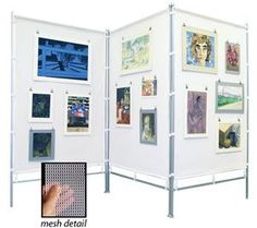 a white room divider with pictures on the wall and a hand pointing at it