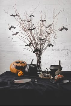 a table topped with lots of halloween decorations next to a white brick wall in the background