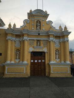 an old yellow church with statues on the front