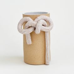 a vase with two white rings tied to it's sides, sitting on a table