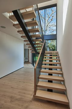 a wooden staircase with black handrails next to a window