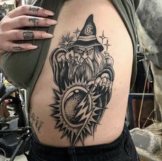 a woman with a tattoo on her stomach wearing a wizard hat and holding a clock