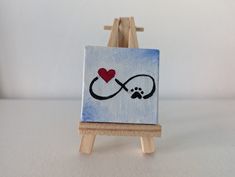 a small easel with a painting on it and a red heart in the middle