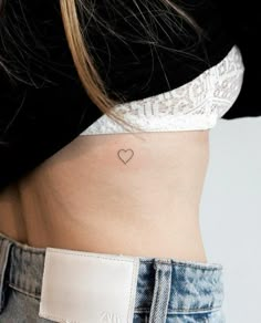 a woman with a small heart tattoo on her stomach