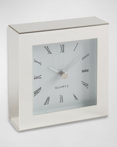 a white square clock with roman numerals on the face and numbers in silver