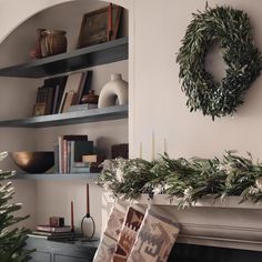 a christmas tree is in front of a fireplace with stockings on it and a wreath hanging over the mantel