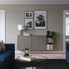 a living room with blue couches and pictures on the wall above them in front of a coffee table