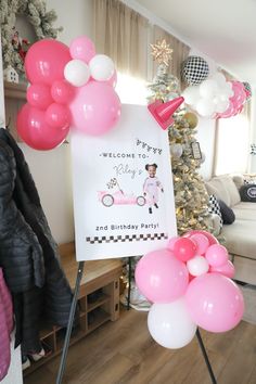 pink and white balloons are in front of a welcome sign