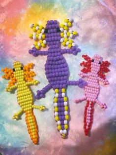 three beaded dolls sitting on top of a tie dyed cloth covered in multicolored beads