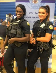 two female police officers standing next to each other in front of a sign that says,