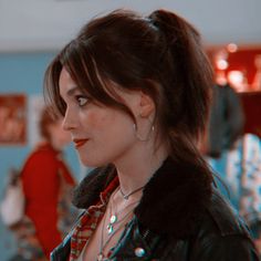 a woman in a black leather jacket looking off into the distance