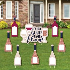 some wine bottles and glasses are in front of a house with a sign that says let the good times go on