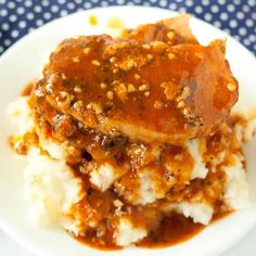 a white plate topped with mashed potatoes covered in gravy and meat sauce