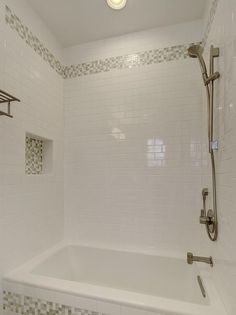 a bathroom with white tiled walls and bathtub, shower head and faucet