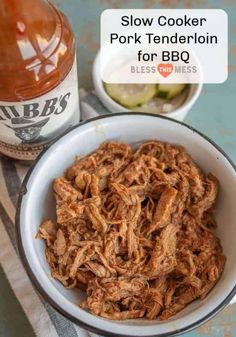 slow cooker pork tenderloin for bbq in a bowl next to a bottle of bbq