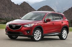 a red mazda cx - 5 parked in front of mountains