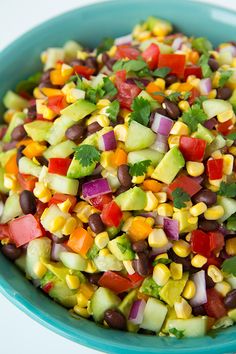 a colorful salad in a blue bowl on a white table