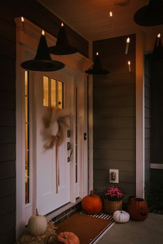 a front porch decorated for halloween with pumpkins, hay and lights hanging from the ceiling