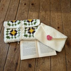 an open book laying on top of a wooden floor next to a crocheted bag