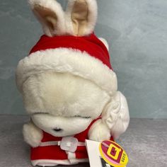 a white stuffed animal wearing a red and white santa hat with ears on it's head