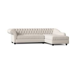 a white sectional couch with black legs and tufted upholstered backrests