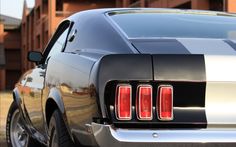 the rear end of a black and silver mustang