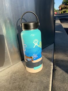 a blue water bottle sitting on the side of a road next to a metal wall