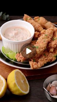 a plate with some fried food on it next to lemon wedges and other foods