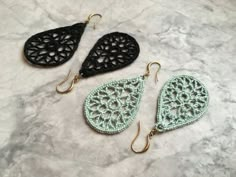 three pairs of crocheted earrings on a marble surface