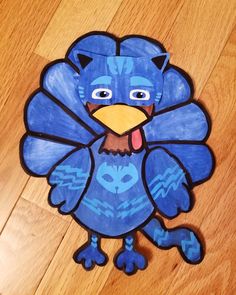 a paper cut out of a blue bird on top of a wooden floor next to a pair of scissors