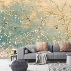 a grey couch sitting in front of a wall with flowers on it and birds flying around