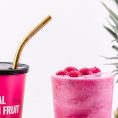 a pink smoothie with raspberries and a gold straw next to a pineapple