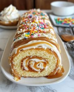 a cake roll covered in frosting and sprinkles on a white plate