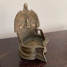 an ornate metal bowl on top of a wooden table