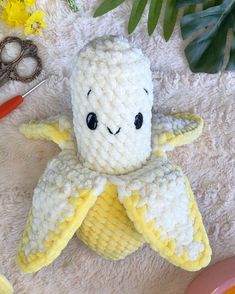 a crocheted stuffed toy sitting on top of a rug next to scissors and flowers