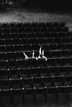 two people laying on their backs in an empty auditorium with rows of seats behind them