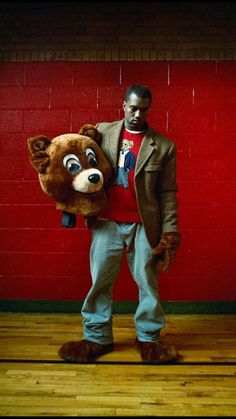 a man holding a large stuffed animal in front of a red wall with the caption, the story behind this picture of ken west