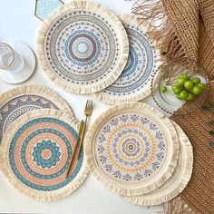 three plates with different designs on them sitting on a table next to wine glasses and grapes