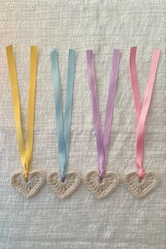 four heart shaped lanyards with ribbons attached to them on a white tablecloth