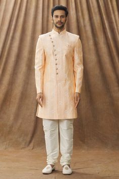 Peach sherwani with floral embroidery. Paired with cream churidar.
Component: 2
Pattern: Embroidered
Type Of Work: Floral
Neckline: Mandarin Collar
Sleeve Type: Full
Fabric: Sherwani: Art silk, Churidar: Dupion art silk, Lining: Faux satin
Color: Peach
Other Details: 
Note: The pocket square worn by the model is not for sale
Occasion: Wedding - Aza Fashions Peach Embroidered Kurta For Wedding, Orange Zari Work Sherwani For Wedding, Orange Sherwani With Zari Work For Wedding, Orange Wedding Sherwani With Zari Work, Peach Wedding Traditional Wear With Chikankari Embroidery, Wedding Orange Sherwani With Zari Work, Orange Sherwani For Wedding Eid Festival, Orange Sherwani For Wedding And Eid, Orange Sherwani For Wedding At Eid