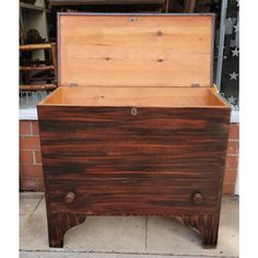 an old wooden chest sitting on top of a cement floor next to a brick wall