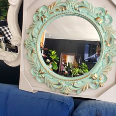 a mirror sitting on top of a blue couch next to a wall mounted planter