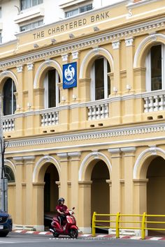 a person on a motor scooter in front of a bank