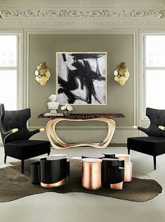 an elegant living room with black chairs and gold accents on the table, along with art work